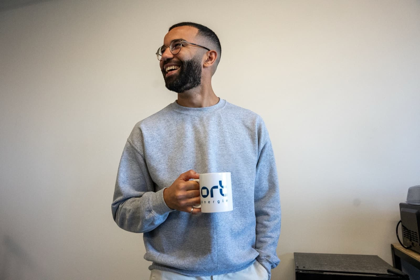 Membre de l’équipe d’ORT Énergie, tasse à la main, dans les bureaux